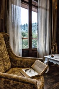 a book and glasses on a couch with a window at Nymfasia Resort in Vytina