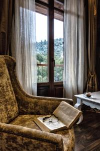 ヴィティナにあるNymfasia Resortの窓のあるソファに掛けた本と眼鏡