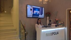 a woman standing at a counter with a television on the wall at Boutique Hotel Melissa in Poreč