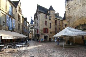 a group of buildings with tables and chairs in a street at Le Royere in Sarlat-la-Canéda