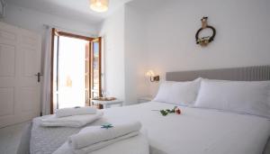 a bedroom with a white bed with towels on it at Andreas and Petrinela Rooms in Triovasálos