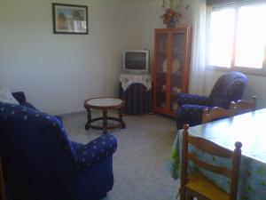 - un salon avec des chaises, une table et une télévision dans l'établissement Verde y Mar, à Noalla