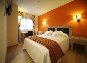 a bedroom with a large bed with an orange wall at Casa Santos in Albalate de Cinca