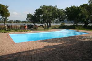 a blue swimming pool with trees in the background at Keurbooms River Lodge 1014 in Plettenberg Bay