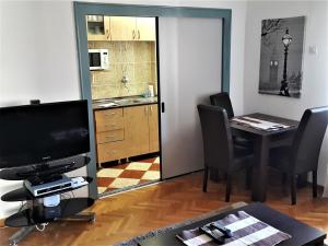 sala de estar con TV y mesa con sillas en Centre Point Apartment en Podgorica