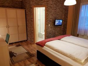 ein Schlafzimmer mit einem Bett und einem TV an einer Backsteinwand in der Unterkunft Legend Hotel in Biebesheim