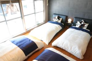 three beds in a room with a large window at Chidori Inn Fukuromachi Hiroshima in Hiroshima