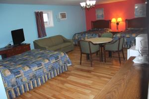 ein Hotelzimmer mit 2 Betten, einem Tisch und Stühlen in der Unterkunft Colonial Motel in Chatham