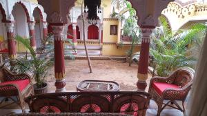a room with a table and chairs and palm trees at Sureli Haveli in Jaipur