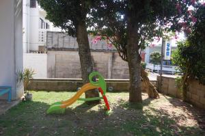 a green and orange slide next to a tree at Minshuku Namisou in Iriomote