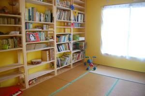 a room with book shelves filled with books at Minshuku Namisou in Iriomote
