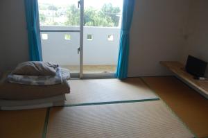 a room with a bed and a large window at Minshuku Namisou in Iriomote