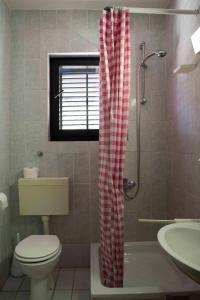 a bathroom with a red and white checkered shower curtain at Guest House Alek in Vrboska