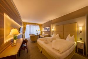 um quarto de hotel com uma cama grande e uma secretária em Dominik Alpine City Wellness Hotel - Adults only em Bressanone
