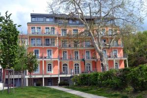 an orange building with a tree in front of it at Hotel Grazerhof in Bad Gleichenberg