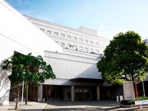 a large white building with trees in front of it at Fukuoka Recent Hotel in Fukuoka