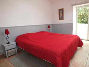 ein Schlafzimmer mit einem roten Bett mit einer roten Decke in der Unterkunft Gîte - La Rigaudière in Le Theil-de-Bretagne