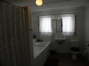 a bathroom with a tub and a toilet and a sink at Honne-Hemel Oubaas in Hondeklipbaai