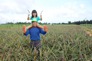 a man holding a little girl on his shoulders in a field at Minshuku Namisou in Iriomote