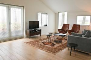 a living room with a couch and chairs and a tv at Residentie De Hoek in Den Dungen