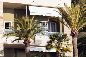two palm trees in front of a building at Residence Sole Mare Alaxi Hotels in Alassio