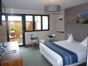 a bedroom with a bed and a balcony with chairs at Hôtel des Rochers in Perros-Guirec