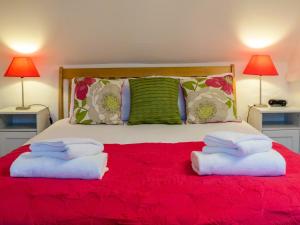 オールドバラにあるThimble Cottageの赤いベッドにタオル2枚を用意したベッドルーム1室