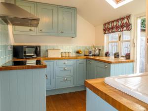 a kitchen with blue cabinets and a sink at Thimble Cottage in Aldeburgh
