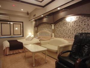 a room with a bed and a couch and a chair at Hotel Hyper Noah (Adult Only) in Sakai