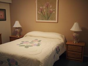 a bedroom with a bed and two tables with lamps at Whale's Tail Guest Suites in Ucluelet