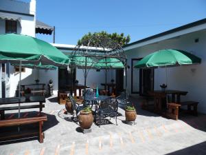 a patio with tables and green umbrellas at Myrtles Retreat in Stilbaai