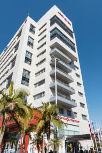 a tall white building with palm trees in front of it at Leonardo Boutique Rehovot in Rechovot