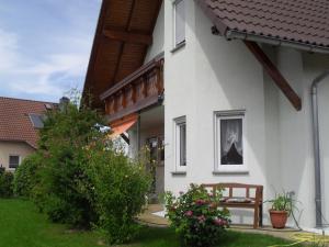 ein weißes Haus mit einer Bank im Hof in der Unterkunft Zimmervermietung im Eigenheim in Göda