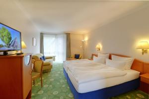 ein Hotelzimmer mit einem großen Bett und einem TV in der Unterkunft Landhotel Zur Eiche in Buxtehude