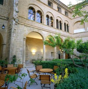 un patio con mesas y sillas frente a un edificio en Parador de Alcañiz, en Alcañiz