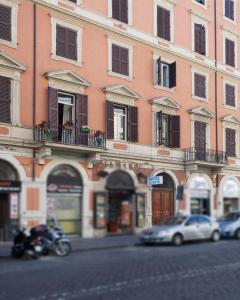 un bâtiment avec des voitures et une moto garées dans une rue dans l'établissement Hotel Oriente, à Rome