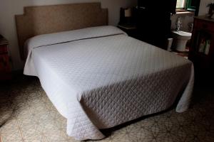 a bed with a white comforter on top of it at Ai Cipressi in Salemi