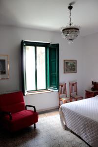 a bedroom with a bed and a red chair and a window at Ai Cipressi in Salemi
