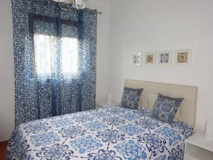 a bedroom with a blue and white bed with a window at Bom dia Porto in Vila Nova de Gaia