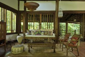 a living room with a couch and chairs and windows at Casa Sertão de Camburi in Camburi