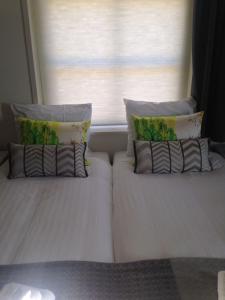 two beds with pillows and pillows in front of a window at Bed & Breakfast Geesberge in Maarssen