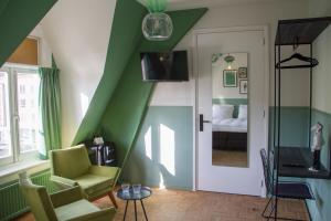 a living room with green walls and a chair and a door at Little Duke Hotel in Den Bosch