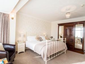 a bedroom with a white bed and a chair at The Coast Yard B & B and Garden Chalets in Chichester