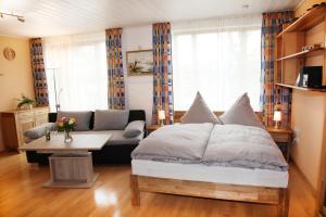 ein Schlafzimmer mit einem Bett, einem Sofa und einem Tisch in der Unterkunft Chiemsee Comfort-Bungalow mit Garten in Rimsting