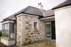 een stenen huis met een raam aan de zijkant bij Scion Hill Gate Lodge in Hillsborough
