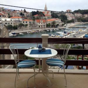 a table and chairs on a balcony with a view of a harbor at Studio Apartment Riva in Sumartin