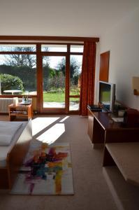 a living room with a bed and a desk with a computer at Hotel Garni Reulein in Lindau