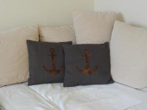 a bed with two pillows with a anchor on it at Land & Meer in Hasselberg