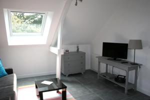 ein Wohnzimmer mit einem TV und einem Schreibtisch mit einem TV in der Unterkunft La Cattevillaise in Saint-Pair-sur-Mer
