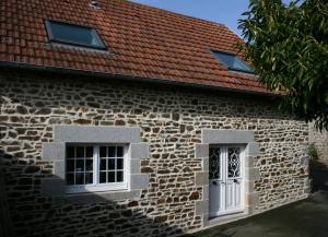 un edificio de piedra con 2 ventanas y techo rojo en La Cattevillaise, en Saint-Pair-sur-Mer